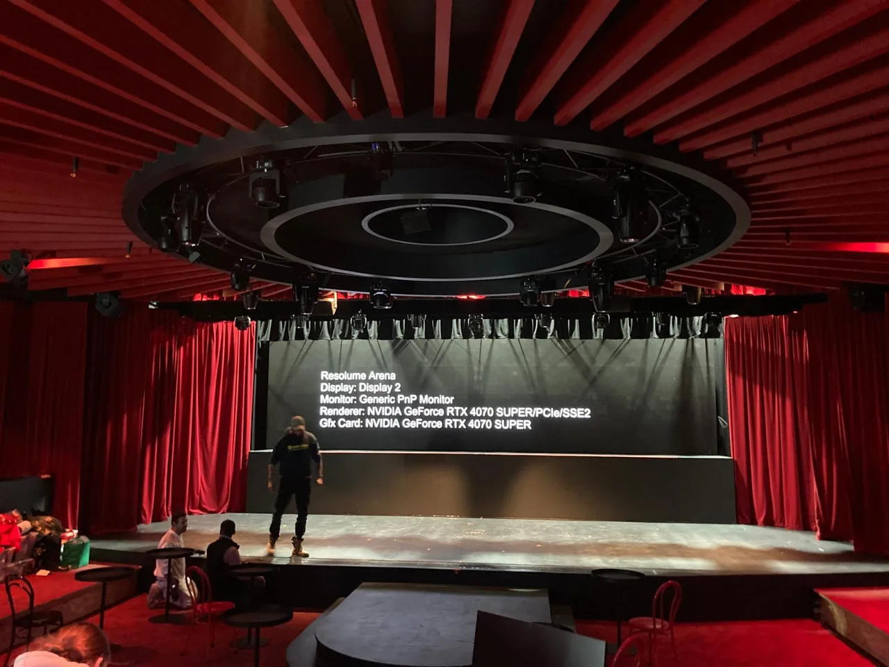 A venue mid-fit-out with red velvet drapes, a circular lighting ring and an LED screen